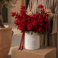 Woman holding a red roses box bouquet by AIWA Flowers Dubai