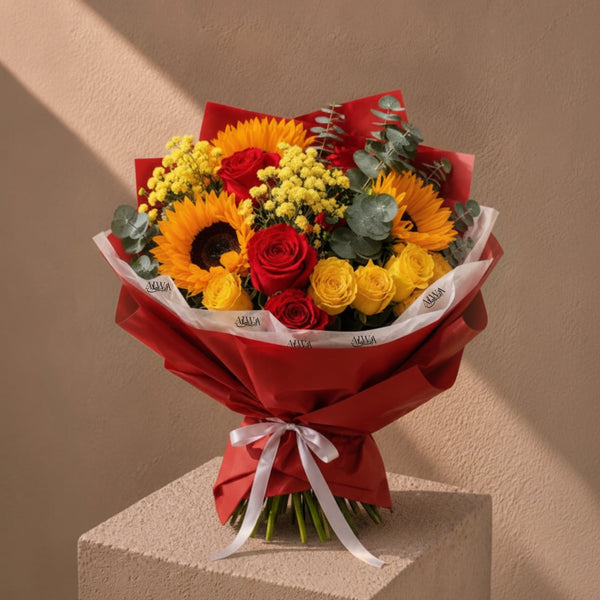 Sunflower, red and yellow rose bouquet in red wrap by AIWA Flowers Dubai