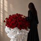 Woman in black holding an oversized red rose bouquet by AIWA Flowers Dubai