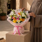 Woman holding a multicolor rose bouquet with butterfly accent by AIWA Flowers Dubai