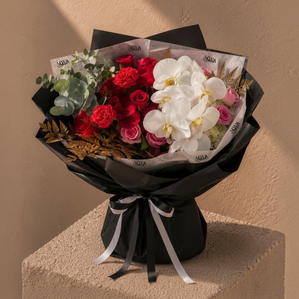Red rose and white orchid bouquet in black wrap by AIWA Flowers Dubai