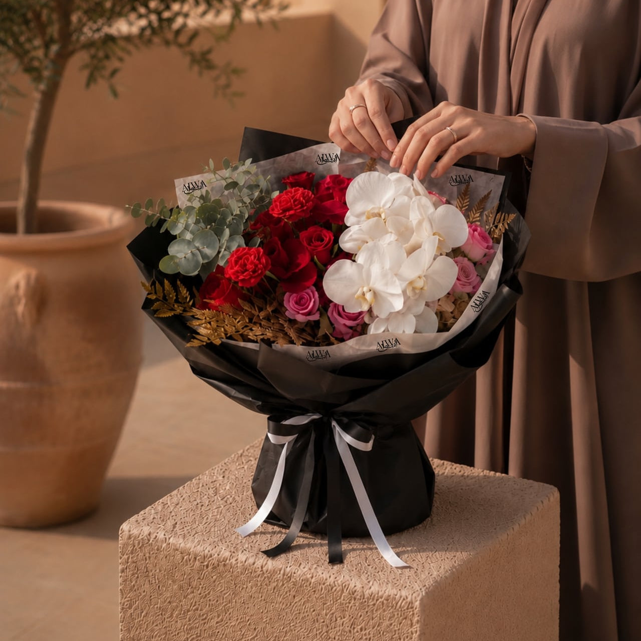 Woman holding a red rose and white orchid bouquet by AIWA Flowers Dubai