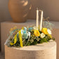 Easter centerpiece with yellow and white roses, blue carnations, and ribbons on moss base, Aiwa Flowers Dubai