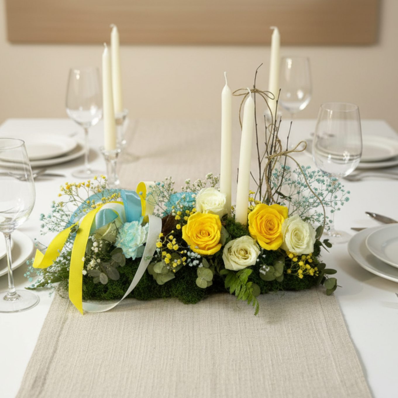 Floral Easter centerpiece with candles, yellow and white roses, and soft blue flowers in elegant styling