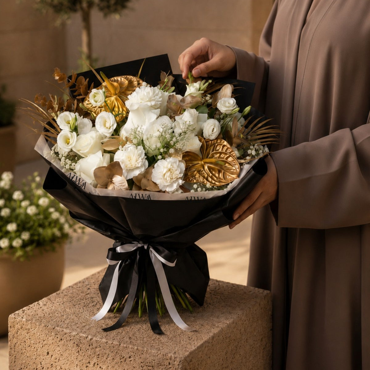 Woman holding a white and gold bouquet by AIWA Flowers Dubai