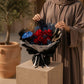 Woman holding a red rose bouquet with blue anthurium by AIWA Flowers Dubai