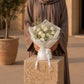 Woman holding a white rose and gypsophila bouquet by AIWA Flowers Dubai