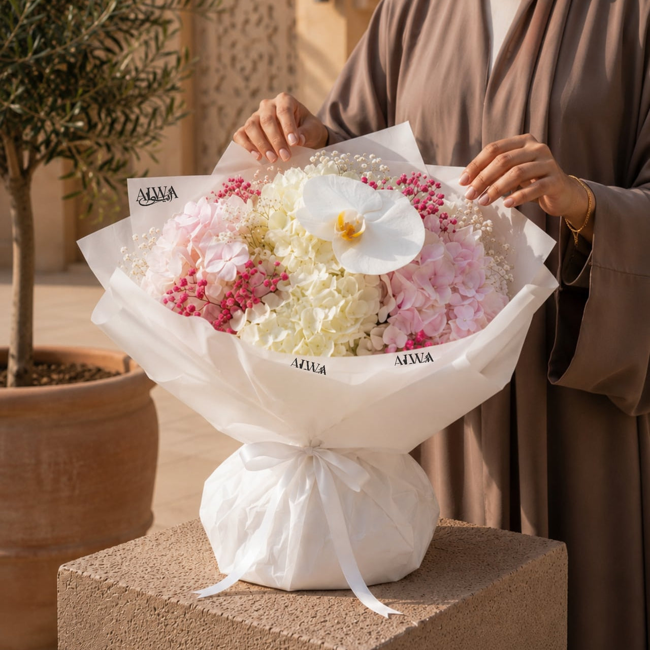 Woman holding a white and pink hydrangea bouquet with orchid by AIWA Flowers Dubai