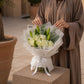 Woman holding a white rose and lily bouquet by AIWA Flowers Dubai
