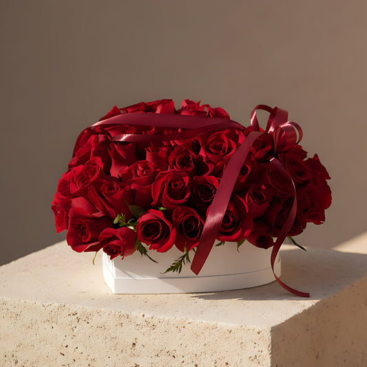 Love Bloom white heart-shaped box with 55 to 65 fresh red roses