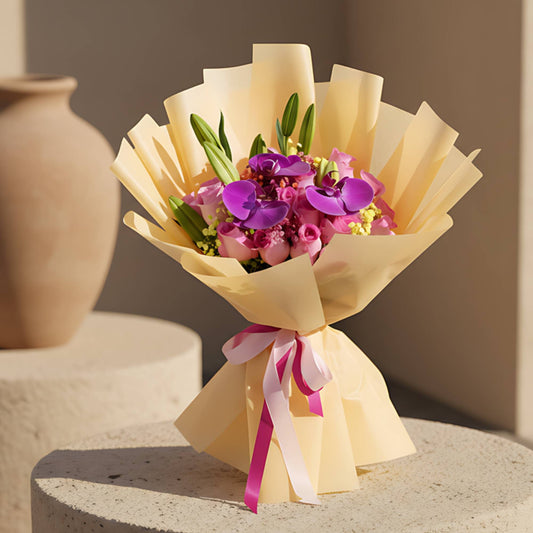 Magenta hand-tied bouquet with pink roses, purple orchids, lilies and gypsophila in gold wrapping