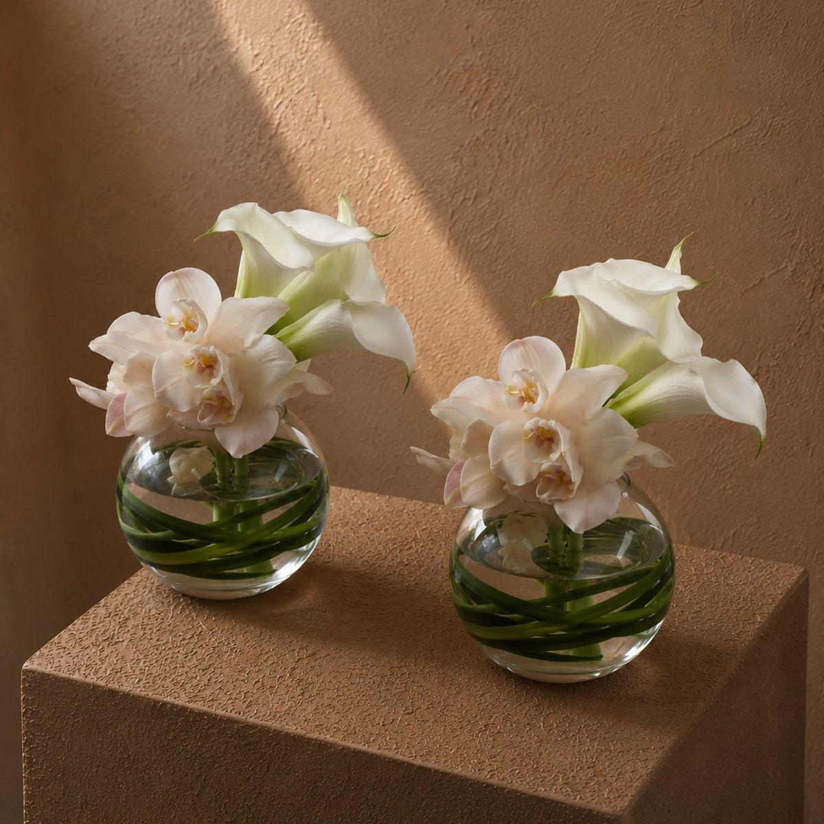 White cymbidium orchids and calla lilies in clear glass bowls - Mila by AIWA Flowers