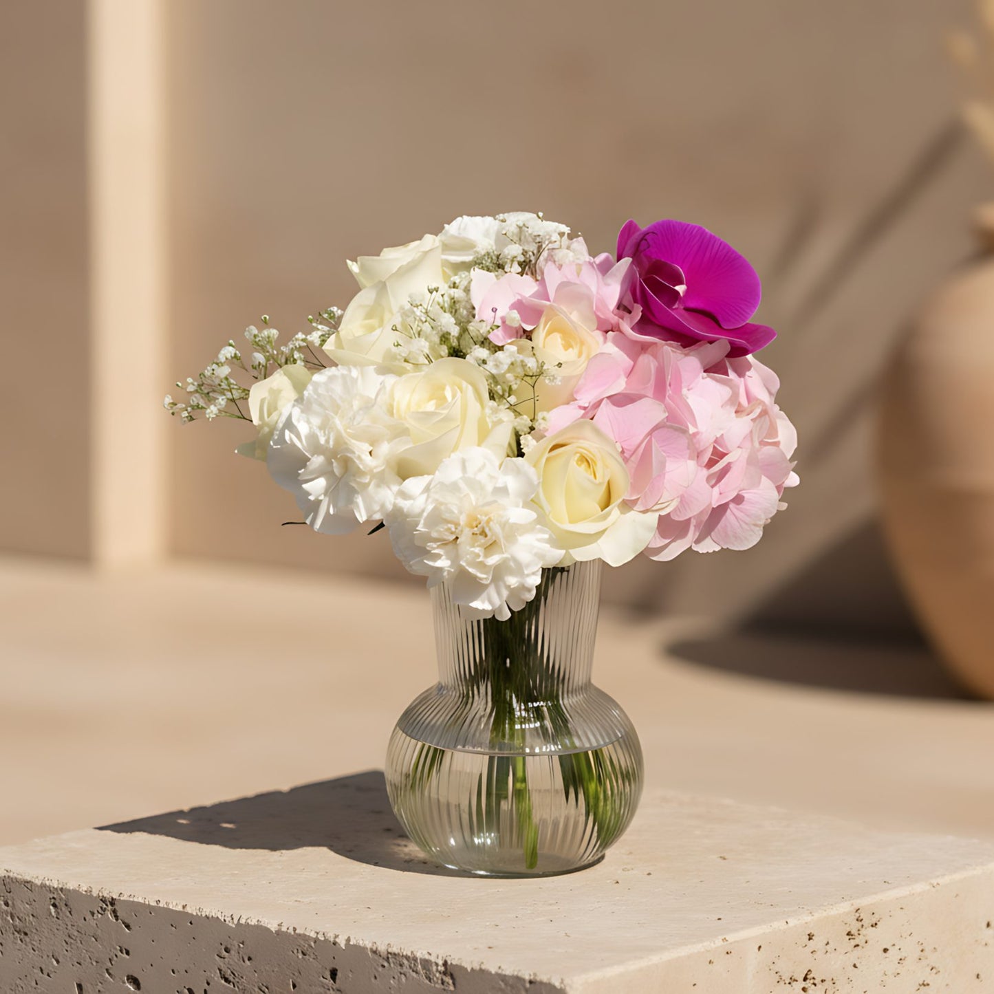 Mila arrangement with white roses, pink hydrangea, purple orchid and gypsophila in a clear glass vase
