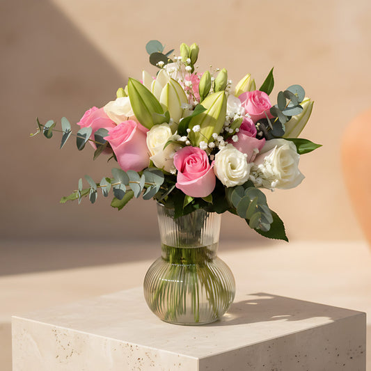Naomi arrangement with pink and white roses, lilies, lisianthus, gypsophila and eucalyptus in a clear glass vase
