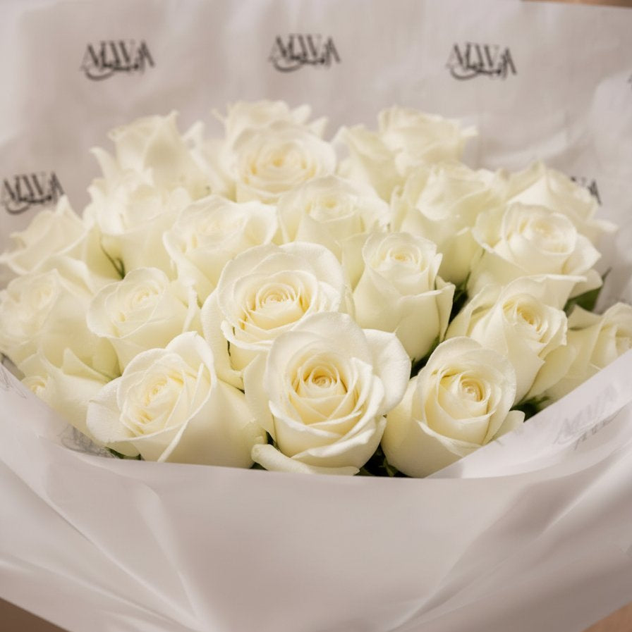 Close-up of pristine white roses in white wrapping by AIWA Flowers