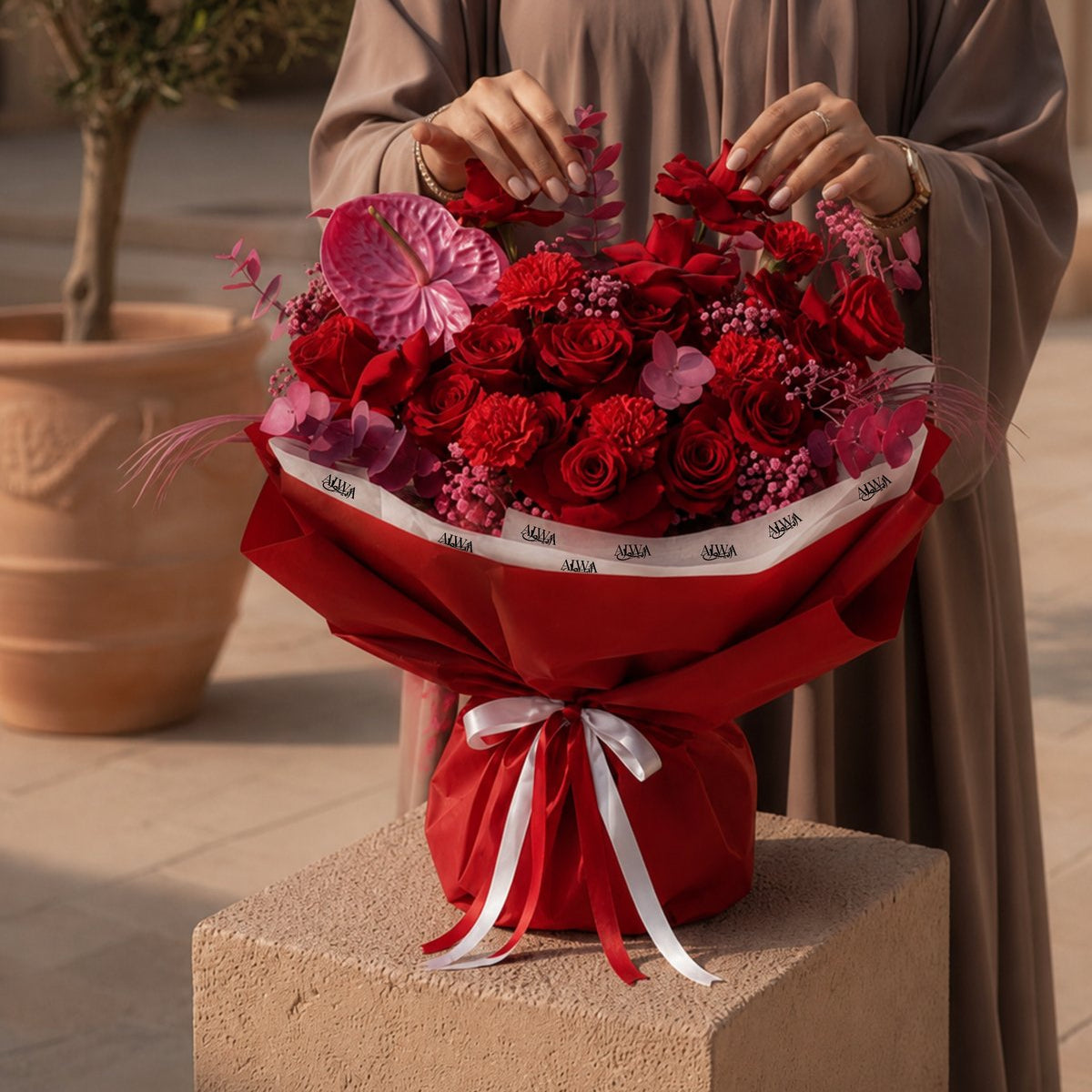 Woman holding a red rose and carnation bouquet with pink accents - Noctelle by AIWA Flowers