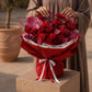 Woman holding a red rose and carnation bouquet with pink accents - Noctelle by AIWA Flowers