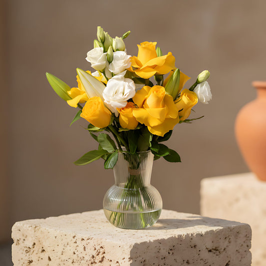 Nova arrangement with yellow roses, lilies and lisianthus in a clear glass vase