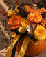 Close-up of orange and yellow roses, black berries and gold leaves in the Omen arrangement
