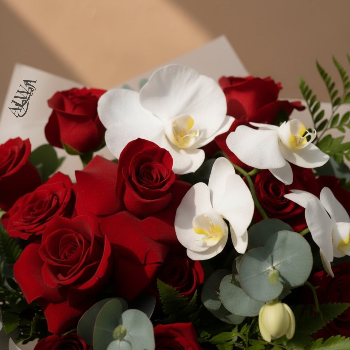 Close-up of red roses and white phalaenopsis orchids with fern by AIWA Flowers