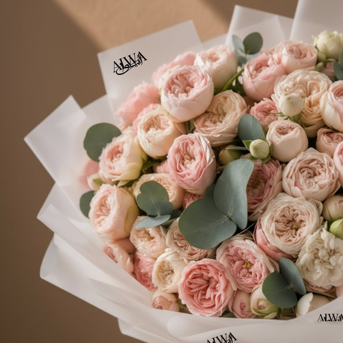 Close-up of ruffled blush and cream garden roses with eucalyptus by AIWA Flowers