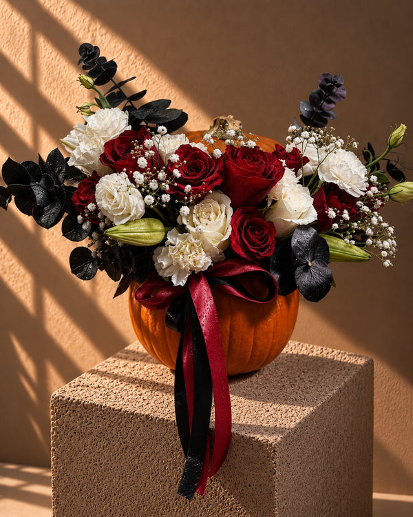 Phantom Halloween arrangement of red and white roses with black foliage in a fresh pumpkin