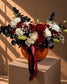 Phantom Halloween arrangement of red and white roses with black foliage in a fresh pumpkin