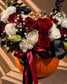 Close-up of red roses, white carnations and black foliage in the Phantom arrangement