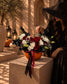 Phantom red and white rose pumpkin arrangement styled beside a woman in a witch hat