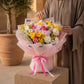 Woman holding a pastel bouquet of pink and yellow roses in pink wrap - Pink Garden by AIWA Flowers