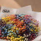 Rainbow gypsophila bouquet in white wrapping on a plinth by AIWA Flowers