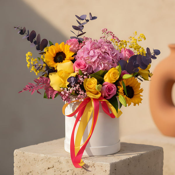 Rising Sun flower box with pink and yellow roses, sunflowers and hydrangea in a white velvet box