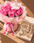 Rosabelle baby gift set with daisy knit bib, booties, pacifier and bow clip beside pink roses