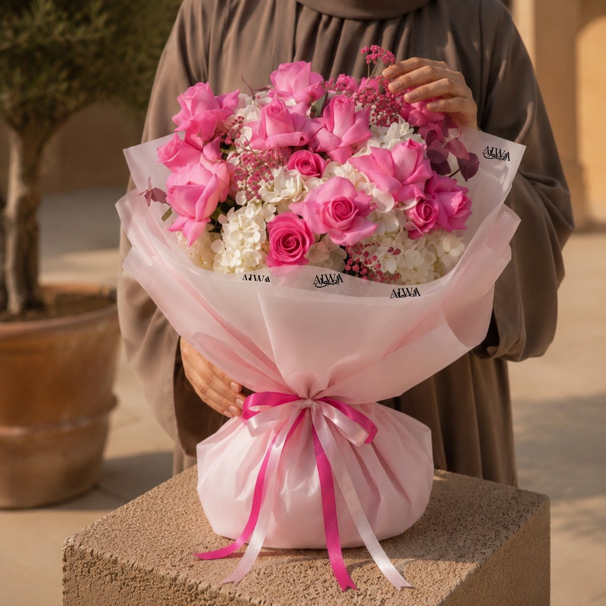 Woman holding a pink rose and white hydrangea bouquet in pink wrap - Rose Amour by AIWA Flowers
