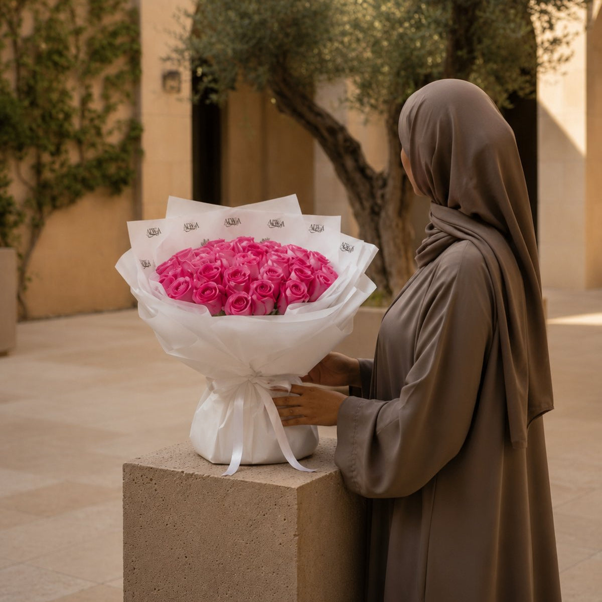 Woman with a bouquet of vibrant pink roses in white wrap - Rose Gelato by AIWA Flowers