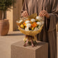 Woman holding a warm gold and orange rose bouquet in cream wrap - Sand Castle by AIWA Flowers