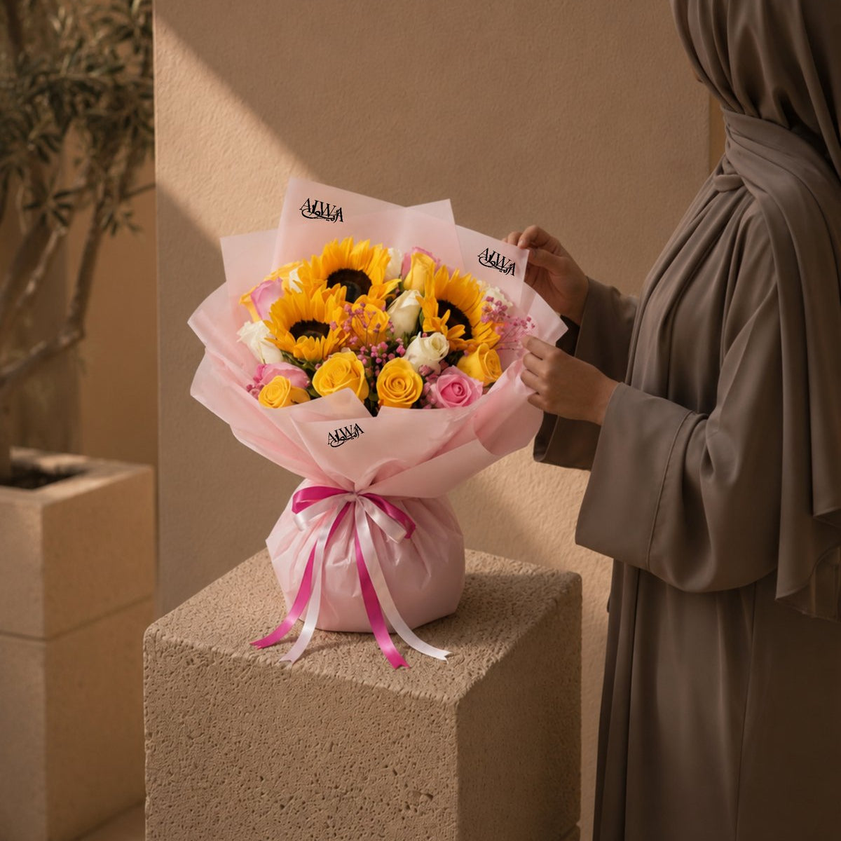 Woman holding a sunflower and pink rose bouquet in pink wrap - Serenity by AIWA Flowers