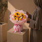 Woman holding a sunflower and pink rose bouquet in pink wrap - Serenity by AIWA Flowers