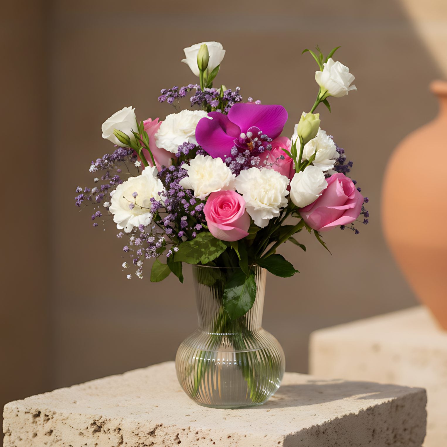 Sophia arrangement with pink roses, white carnations, lisianthus, purple orchid and gypsophila in a clear glass vase