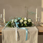 Easter table setting with floral centerpiece featuring white roses, blue ribbons, and bunny decoration, modern spring styling