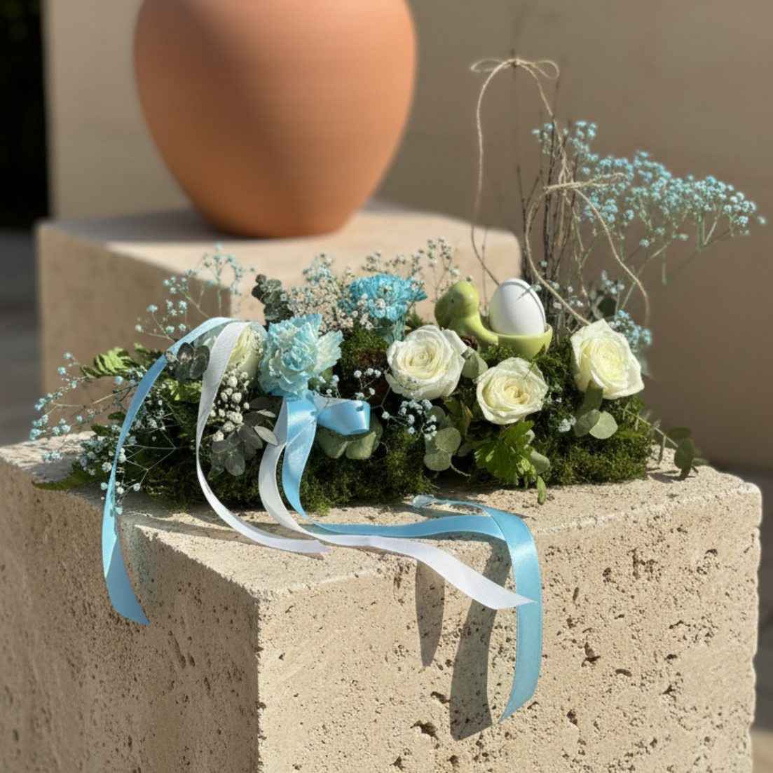 Elegant Easter centerpiece with white roses, blue flowers, and ceramic bunny egg holder on stone pedestal, Aiwa Flowers Dubai