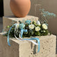 Elegant Easter centerpiece with white roses, blue flowers, and ceramic bunny egg holder on stone pedestal, Aiwa Flowers Dubai