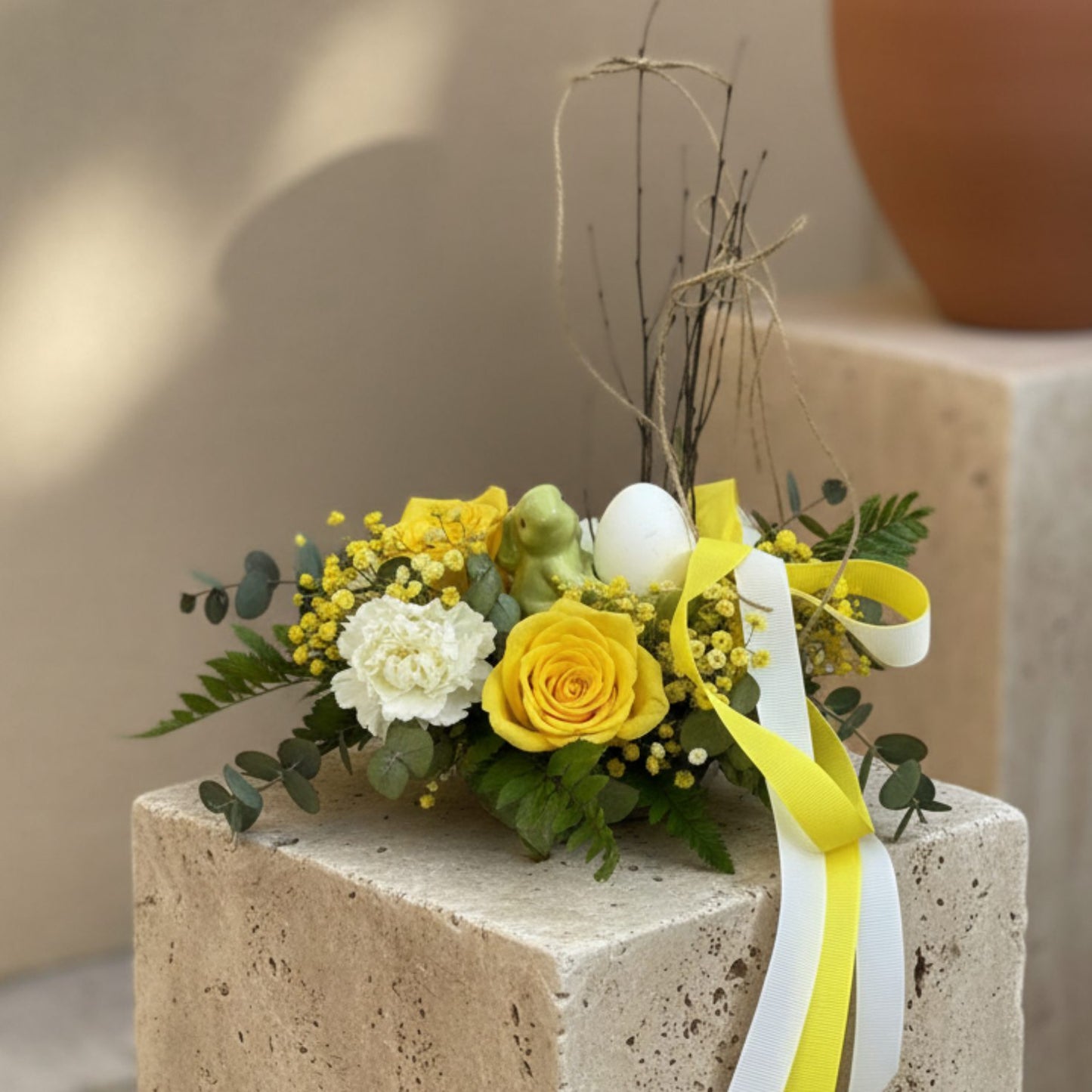 Easter centerpiece with yellow roses, white carnations, and ceramic bunny egg holder on moss base, Aiwa Flowers Dubai