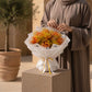 Woman holding a cheerful orange and yellow gypsophila bouquet in white wrap - Sunny by AIWA Flowers