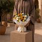 Woman holding Sunrise bouquet of sunflowers, yellow and white roses in white wrap - AIWA Flowers