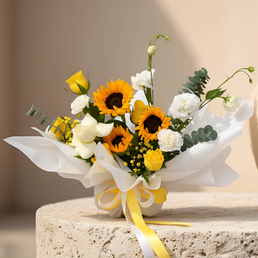 Sunrise hand-tied bouquet with sunflowers, yellow and white roses, lisianthus and eucalyptus in white wrapping