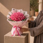 Model holding a large deep pink rose bouquet in soft pink wrap - Thrill by AIWA Flowers