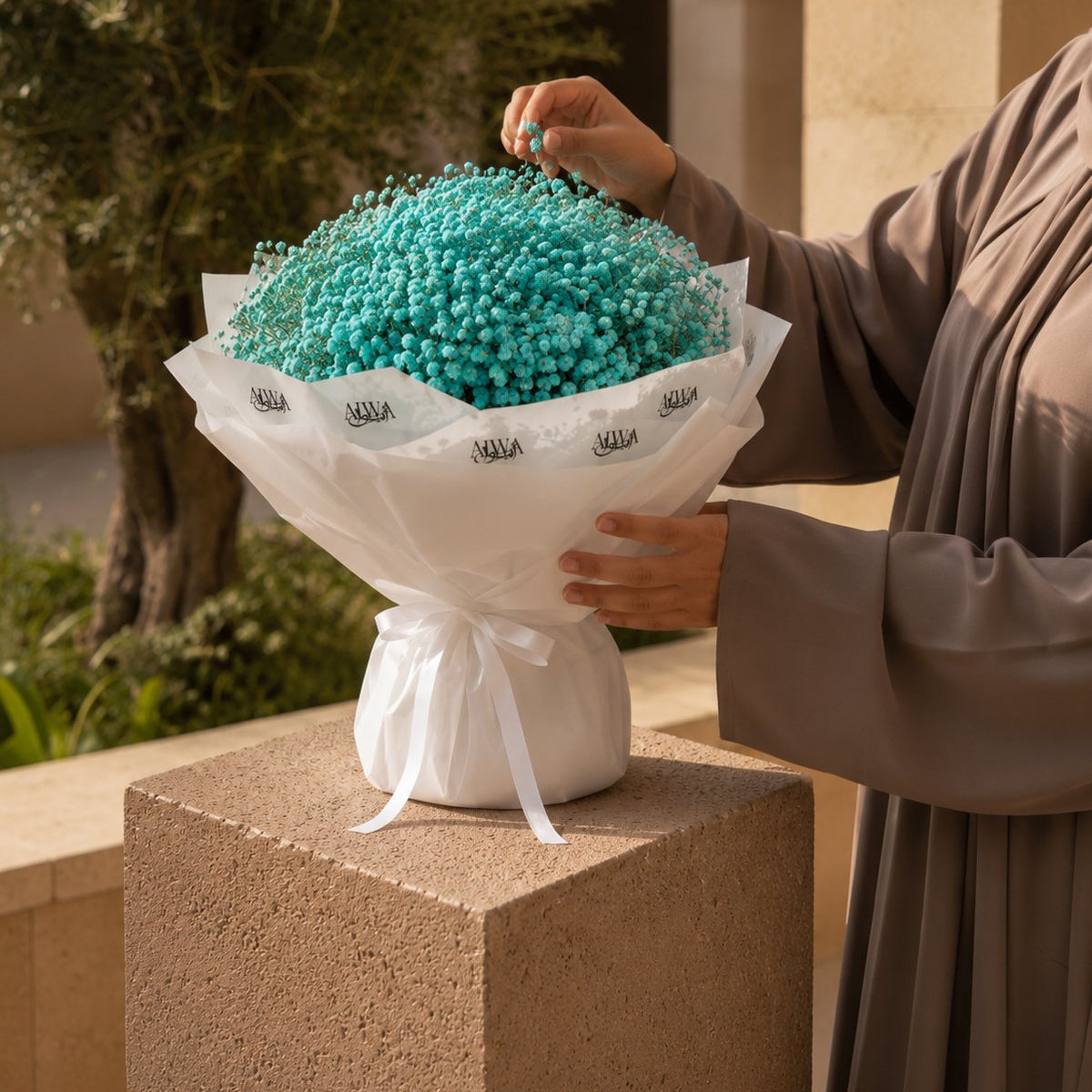 Woman holding a blue gypsophila bouquet in white wrap - Tiffany Sky by AIWA Flowers
