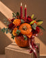 Trick or Treat Halloween centrepiece of orange and red roses with red candles in a fresh pumpkin
