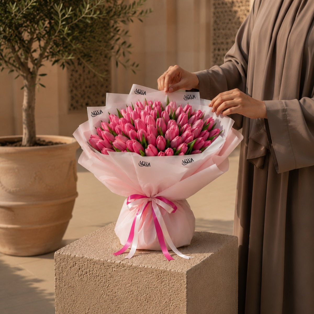 Woman holding a lavish pink tulip bouquet in blush wrap - Tulip Tapestry by AIWA Flowers